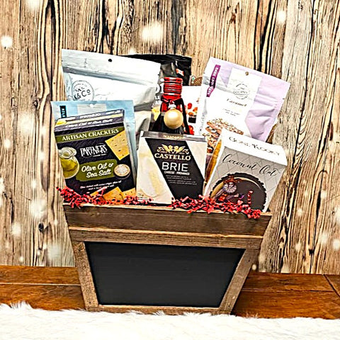 Gift basket with wine, cheese, and crackers on a wooden stand against a rustic wood background.